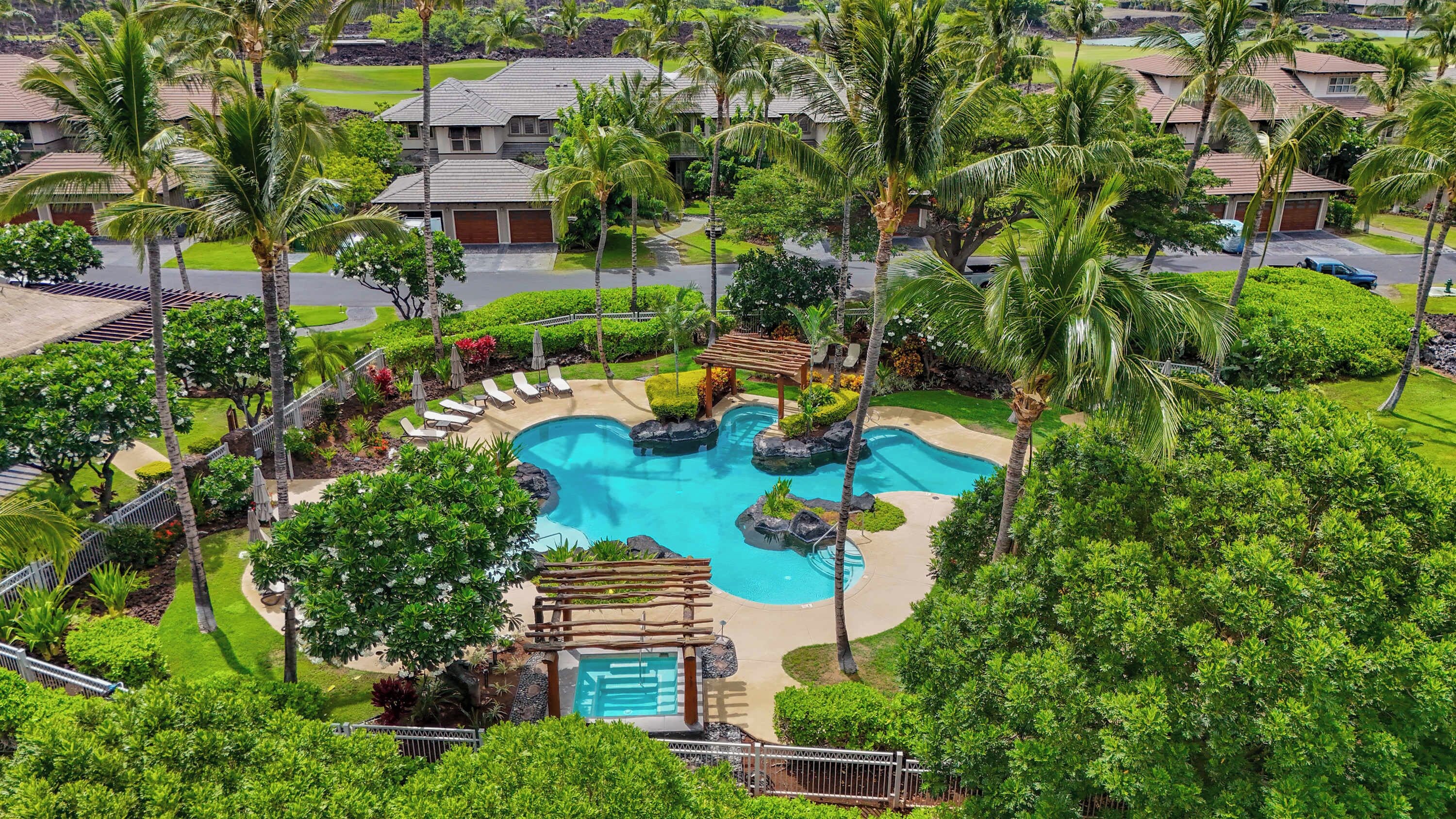 Un resort con piscina, palmeras y césped cuidado.