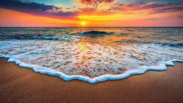 Une plage avec des vagues au coucher du soleil.