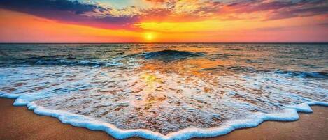 A beach with waves at sunset.