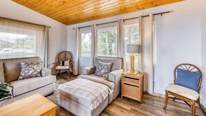 Una habitación acogedora con techo de madera, una cama, un sofá, una silla y una mesita de noche con lámpara.