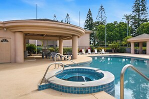 Piscina com hidromassagem, espreguiçadeiras e área de estar coberta.
