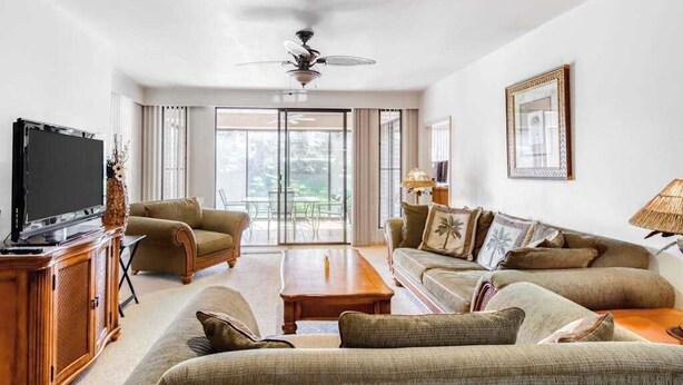 Ein Wohnzimmer mit Fernseher, Sofas, Couchtisch und Deckenventilator.