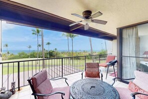 A balcony with a ceiling fan, outdoor seating, and a view of the ocean. - *New* Fall Special Ocean and Golf Views from a Kona Lanai for Four (Kailua-Kona)