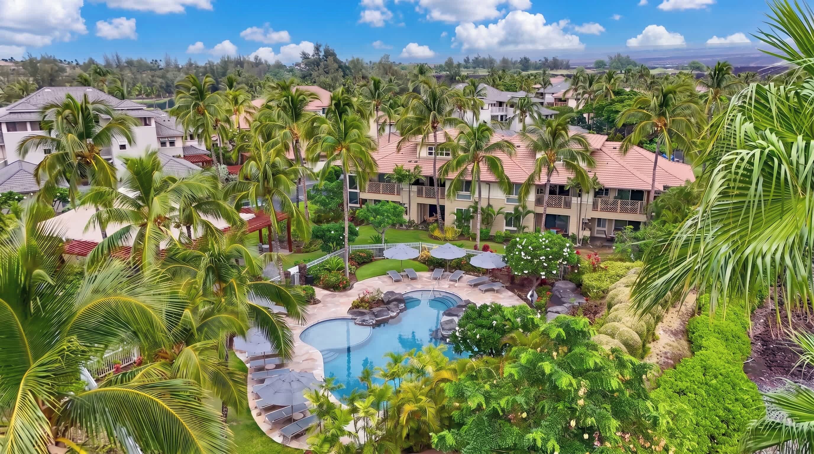 Un resort con piscina rodeada de palmeras y vista al paisaje.