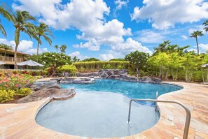 A swimming pool with a rock feature, surrounded by tropical vegetation and a clear sky. - Waikoloa Beach Resort Villa-Golf, Pools, Hot Tub, Local Shops, Dining, Beach Fun (Waikoloa)
