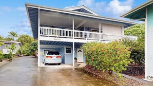 Une maison à deux étages avec un porche avant couvert, un garage et une voiture garée devant.