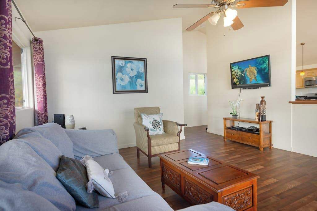 A living room with a sofa, armchair, coffee table, TV, and wooden cabinet.