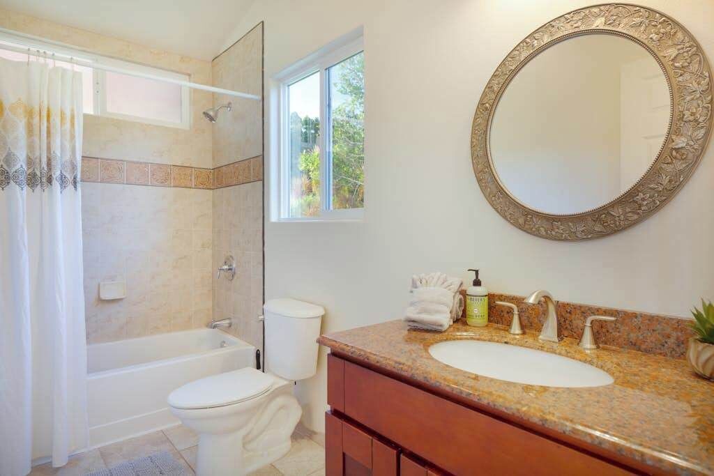 Un baño con bañera, inodoro, lavabo y un espejo grande.