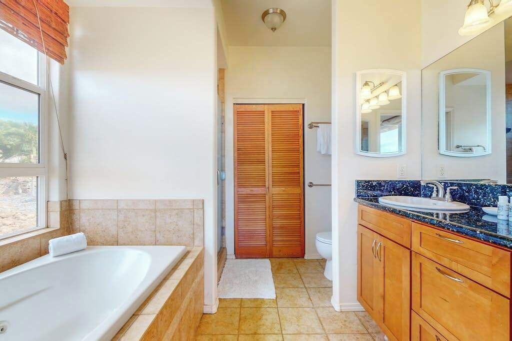 A bathroom with a bathtub, toilet, vanity with a sink, and a mirror.