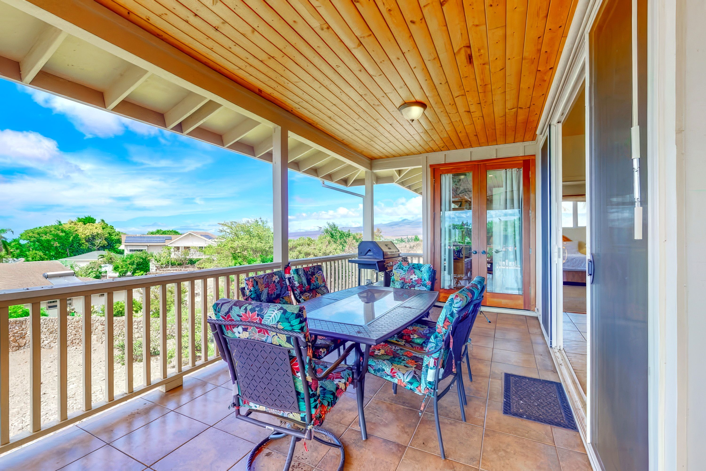 Un patio techado con mesa y sillas, vistas del paisaje y una puerta que da a una habitación.
