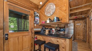 A wooden interior with a kitchen area, bar stools, and a sign indicating Tennessee's whiskey. - Bears in the Mist (Sevierville)