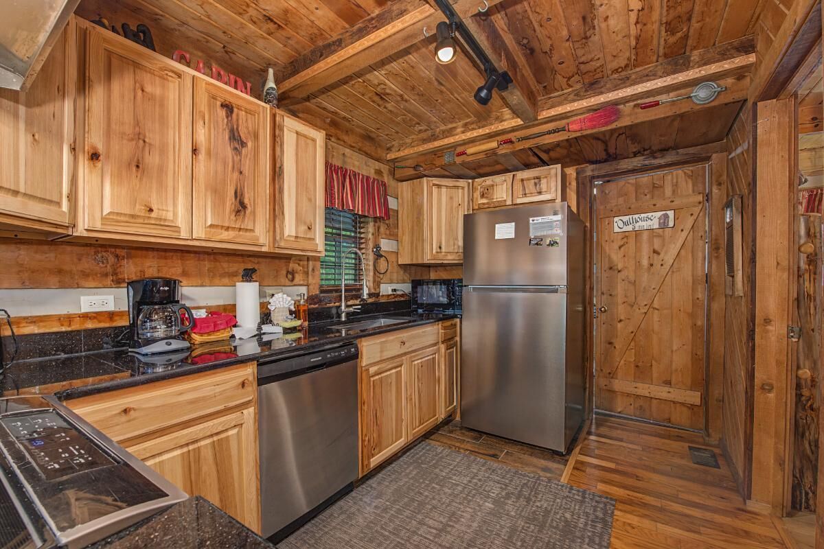 A wooden interior with a stainless steel refrigerator, wooden cabinets, a coffee maker, and a sign on the door.