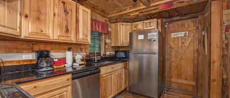 A wooden interior with a stainless steel refrigerator, wooden cabinets, a coffee maker, and a sign on the door.
