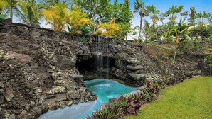 A natural pool with a waterfall, surrounded by tropical vegetation and a stone wall. - NEW Fall Sale Private Infinity Pool Above Kona Coffee Country (Captain Cook)