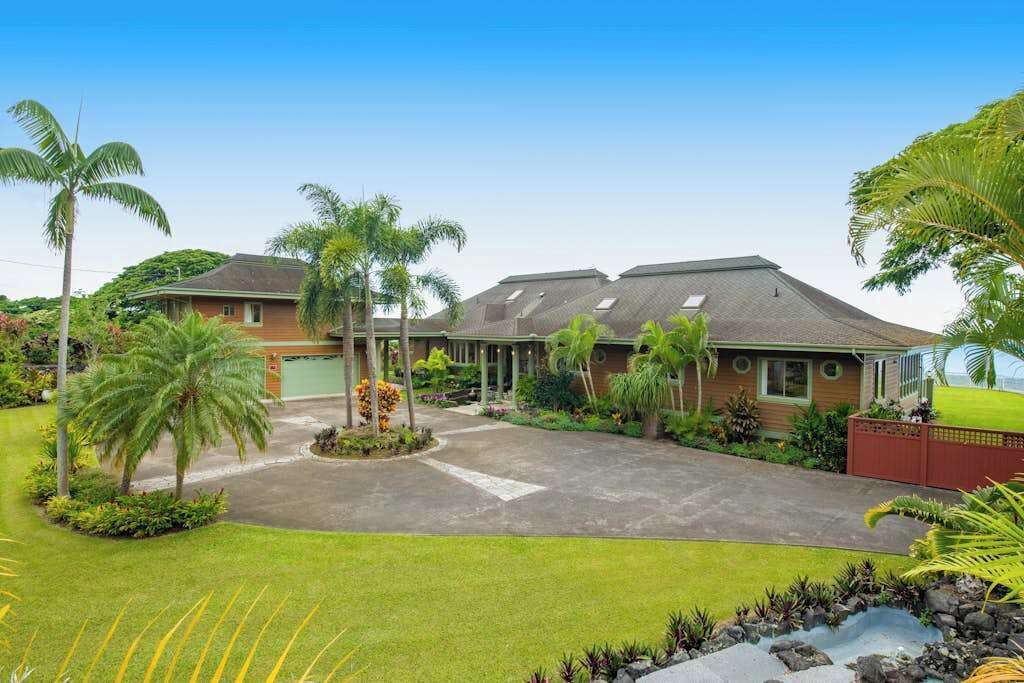 A residential property with a driveway, palm trees, and a well-maintained lawn.