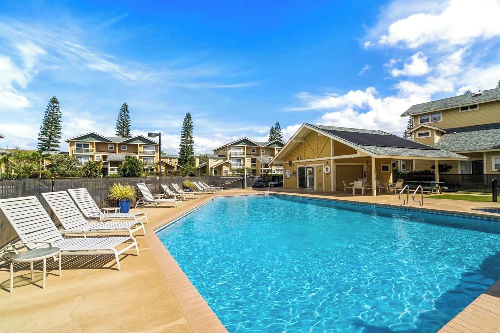 Une piscine avec des chaises longues et un espace patio couvert.