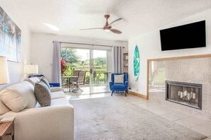 Una sala de estar moderna con un sofá, un sillón azul, una chimenea y un televisor montado en la pared.