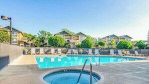 Une piscine dotée de chaises longues et d’un jacuzzi, entourée d’immeubles d’habitation.