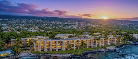 Ein Resort mit mehreren Gebäuden, einem Strand und einer Stadtlandschaft im Hintergrund.