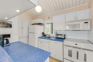 Eine Küche mit weißen Schränken, einer blauen Arbeitsplatte, einer Mikrowelle, einem Toaster, einem Kühlschrank und einem Geschirrspüler.