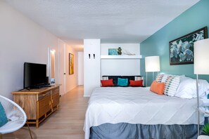 A modern bedroom with a bed, a TV, a desk, and a chair. - Kailua Kona Islander Inn Studio- AC, Pool, Hot Tub, Walk to Beach, Shops, Dining (Kailua-Kona)