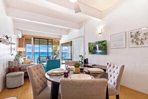 A spacious dining area with a view of the ocean, a large window, and a table set for a meal. - Oceanfront Kona Bali Kai Penthouse 402-AC, Laundry, Pool, WIFI, Magic Sands Area (Kailua-Kona)