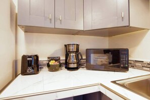A kitchen with a toaster, coffee maker, and microwave on the counter. - NEW Downtown Hilo Bay Base for 31+ Night Stays (Hilo)