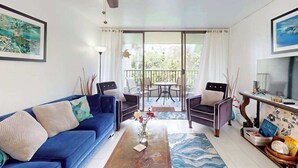 A living room with a blue sofa, two armchairs, a coffee table, and a ceiling fan. - New Fall Deal Hilo 2BR Waterfront Condo by Carlsmith Lagoons (Hilo)