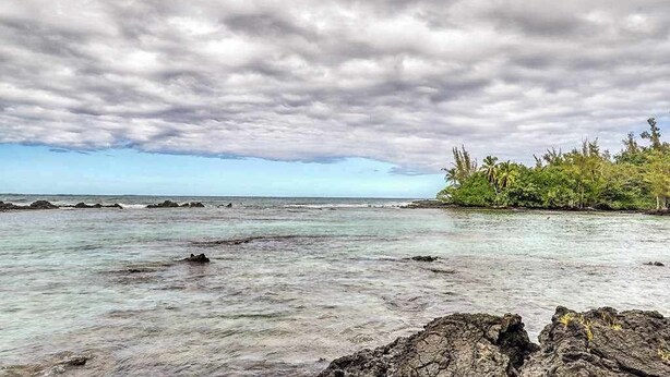 A coastal landscape with rocky shores, clear water, and dense vegetation. - New Fall Deal Hilo 2BR Waterfront Condo by Carlsmith Lagoons (Hilo)