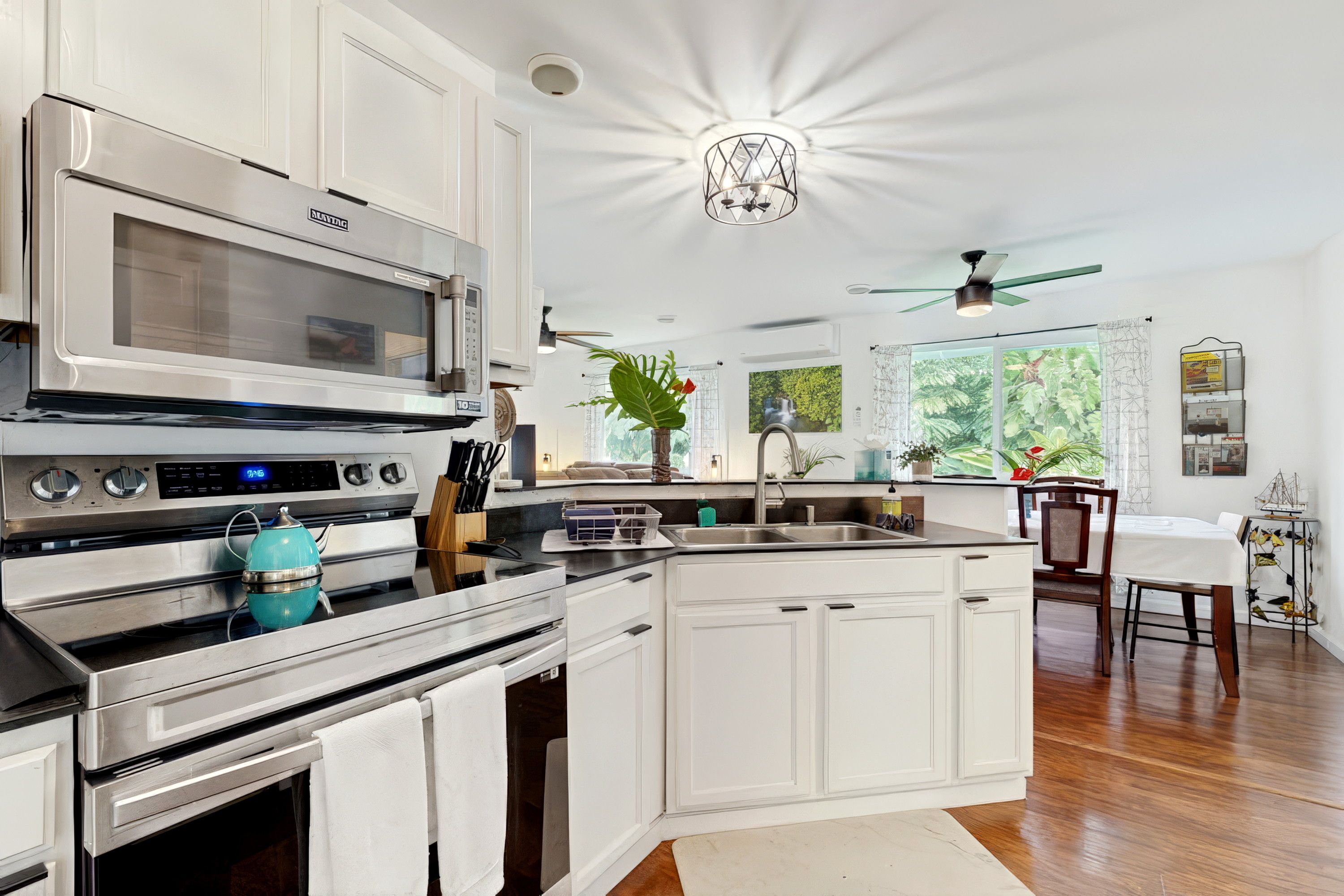 A modern kitchen with stainless steel appliances, a central island, and a dining area with a ceiling fan.