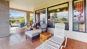 Un área de estar moderna al aire libre con sofá, sillas y sillón reclinable, con vistas a un jardín.