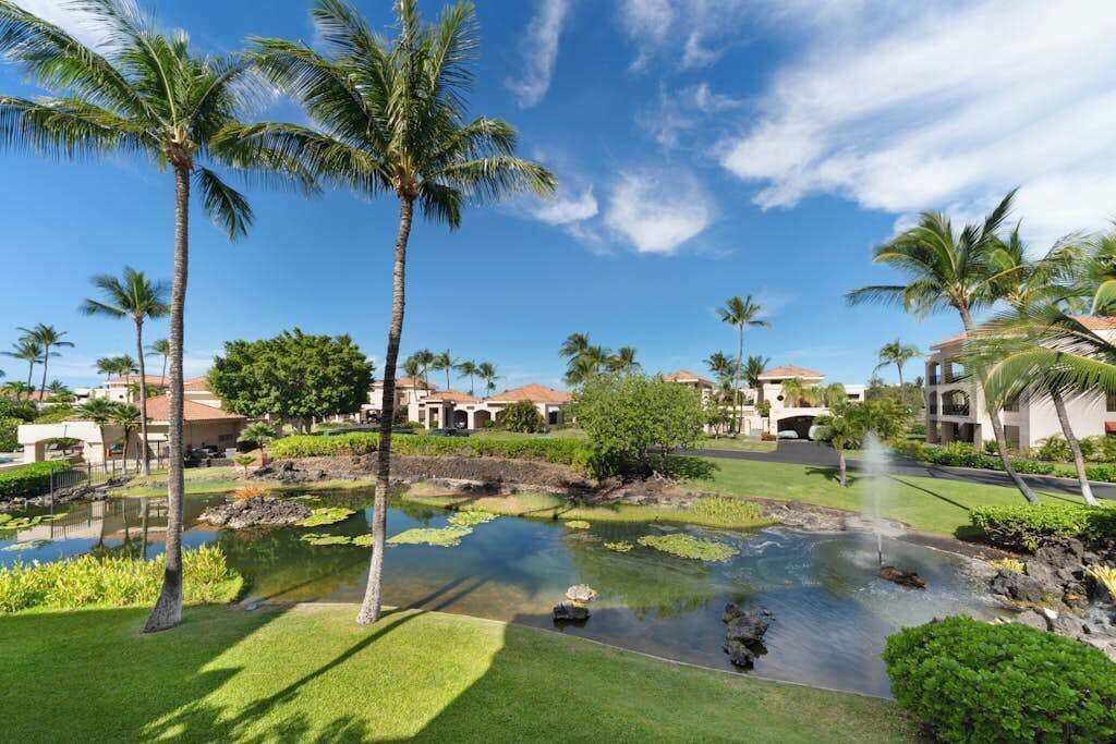 A resort with a water feature, palm trees, and buildings with a clear blue sky.