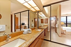 A hotel bathroom with a large mirror, two sinks, a vanity, and a view of the landscape. - *NEW* Top-Floor Waikoloa Escape with Mountain and Golf Views (Waikoloa)