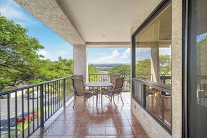 Ein Balkon mit Tisch und Stühlen, Blick auf die Landschaft, und einer Brüstung.
