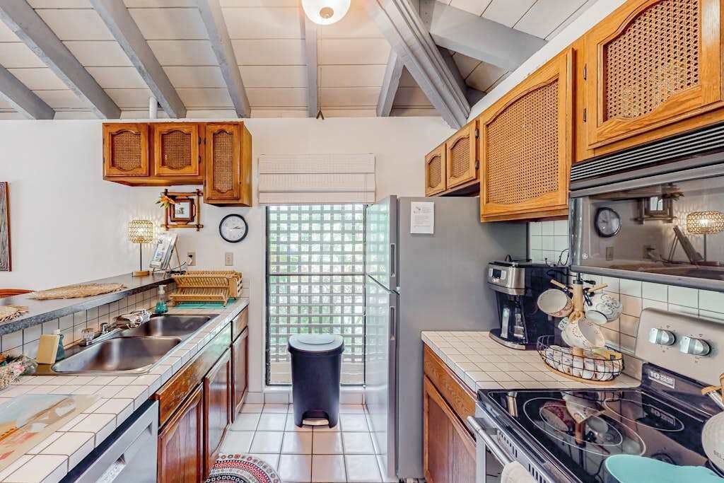 Una cocina compacta con armarios de madera, un refrigerador, una estufa y un lavamanos.
