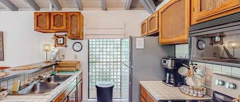 Una cocina compacta con armarios de madera, un refrigerador, una estufa y un lavamanos.