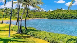 A tropical landscape with palm trees, a beach, and a body of water. - *New* Fall Sale Two-Bedroom Molokai Stay with Balconies and Pool (Kaunakakai)