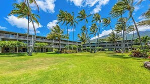 A hotel with a central courtyard, palm trees, and a multi-story building with balconies. - *New* Fall Sale Two-Bedroom Molokai Stay with Balconies and Pool (Kaunakakai)