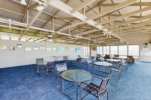 A spacious indoor area with high ceilings, multiple tables and chairs, and framed pictures on the walls. - New Fall $pecial First-Floor Molokai Oceanfront Escape with Pool (Kaunakakai)
