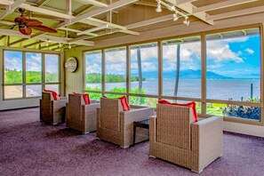 A room with wicker furniture, large windows, and a ceiling fan. - New Fall $ale Shaded Lanai Views Across Molokai's Ocean Channel (Kaunakakai)