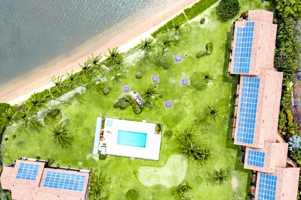 Eine Luftaufnahme eines Resorts mit Pool, Solaranlagen und Strand.