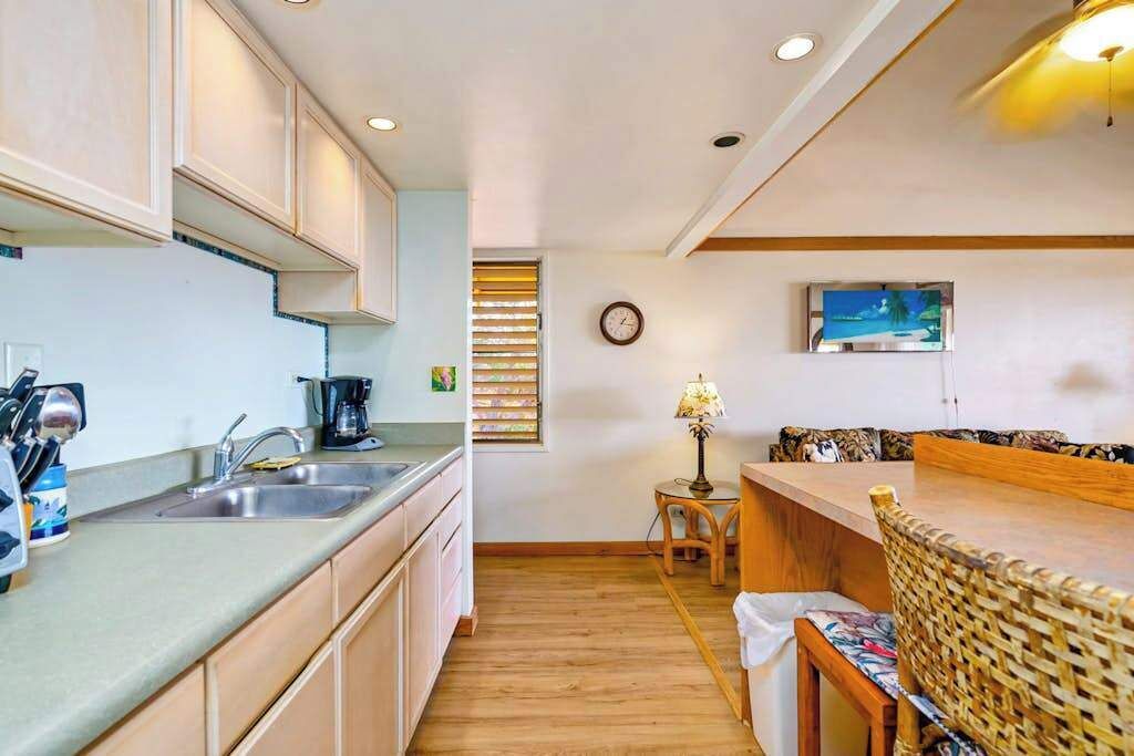A compact kitchen with a sink, stove, and wooden cabinets.