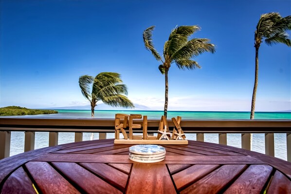 Dining area features wooden table colorful chairs and coastal artwork