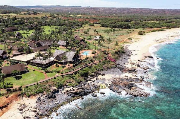 A coastal resort with multiple bungalow-style buildings, a beach, and clear blue waters.
