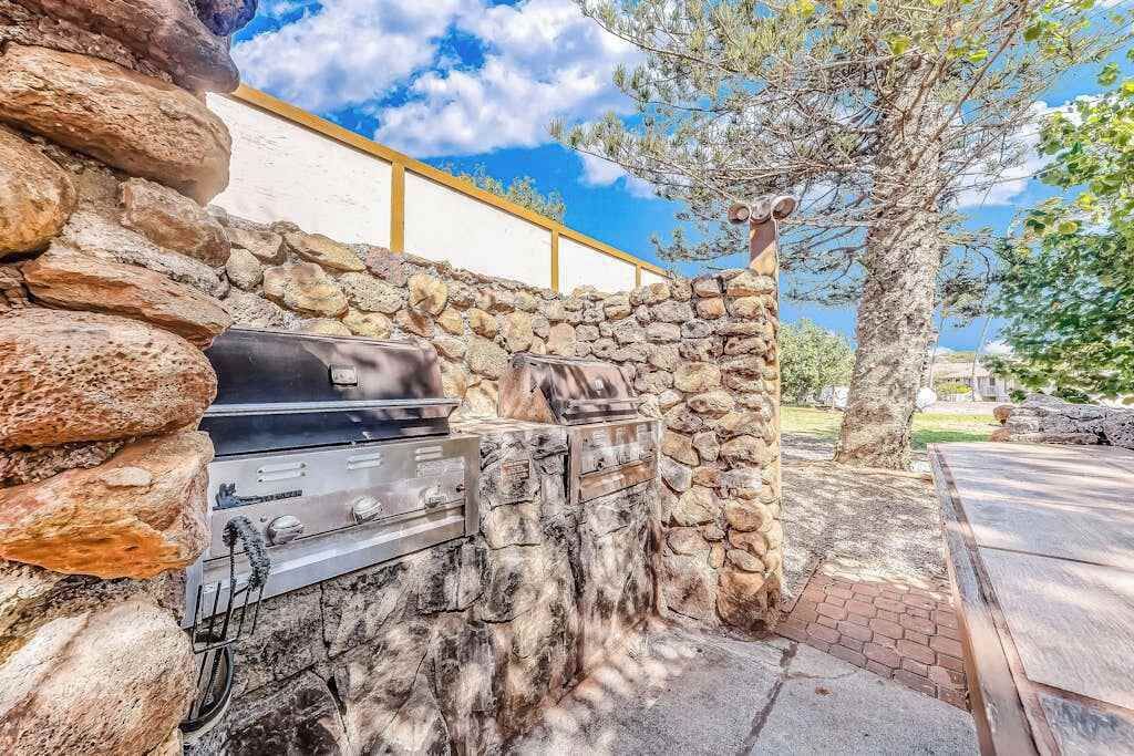 Un muro de piedra con una parrilla y mobiliario exterior.