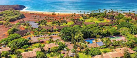 An aerial view of a resort with multiple buildings, a swimming pool, and a beach.
