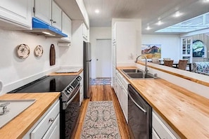 A modern kitchen with wooden countertops, a stove, and a dishwasher. - NEW Fall Sale Colorful Molokai Condo Near Kepuhi Beach with Lanai and Pool (Maunaloa)