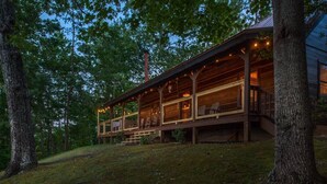 Eine Holzhütte mit Veranda, umgeben von Bäumen.