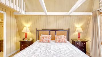 A hotel room with a large bed, two bedside tables with lamps, a wooden headboard, and a balcony.