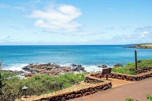 Une vue sur la côte, avec un rivage rocheux, un banc en bois et un ciel dégagé.